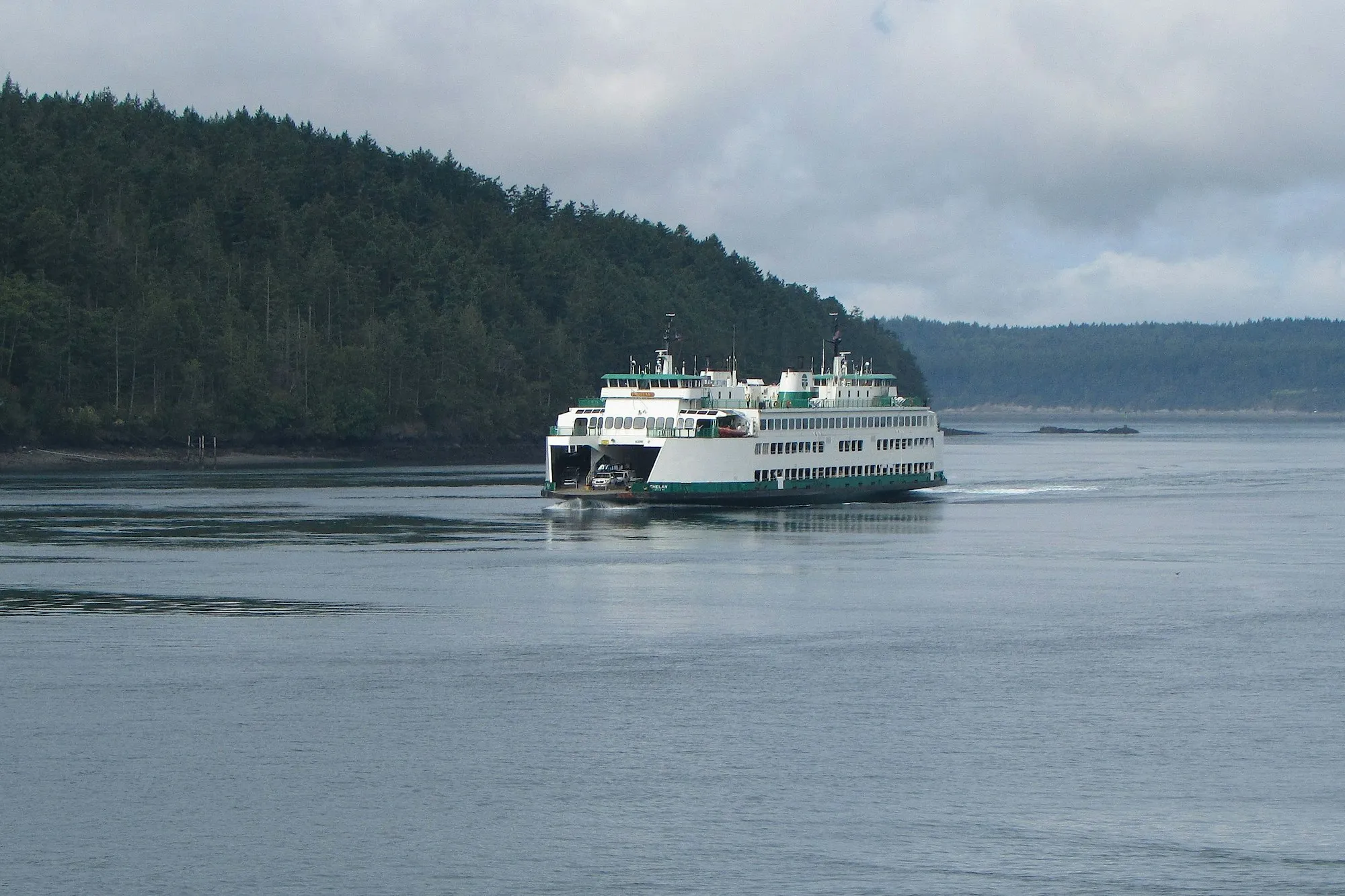 A Washington State ferry crossing Puget Sound past forested shoreline